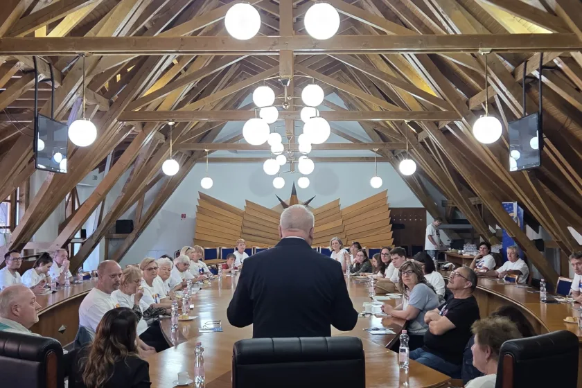 Karaffa Attila, Dunaszerdahely alpolgármestere és a helyi civil szervezetek köszöntik dr. Györfi Beáta és Fábián Bertalan gödöllői alpolgármestereket, Jeney Lászlót, a LISZI elnökét, és a LISZI népes, „Gödöllő 60" pólóban érkező csapatát. A helyszín a dunaszerdahelyi városháza Makovecz Imre által tervezett tanácsterme